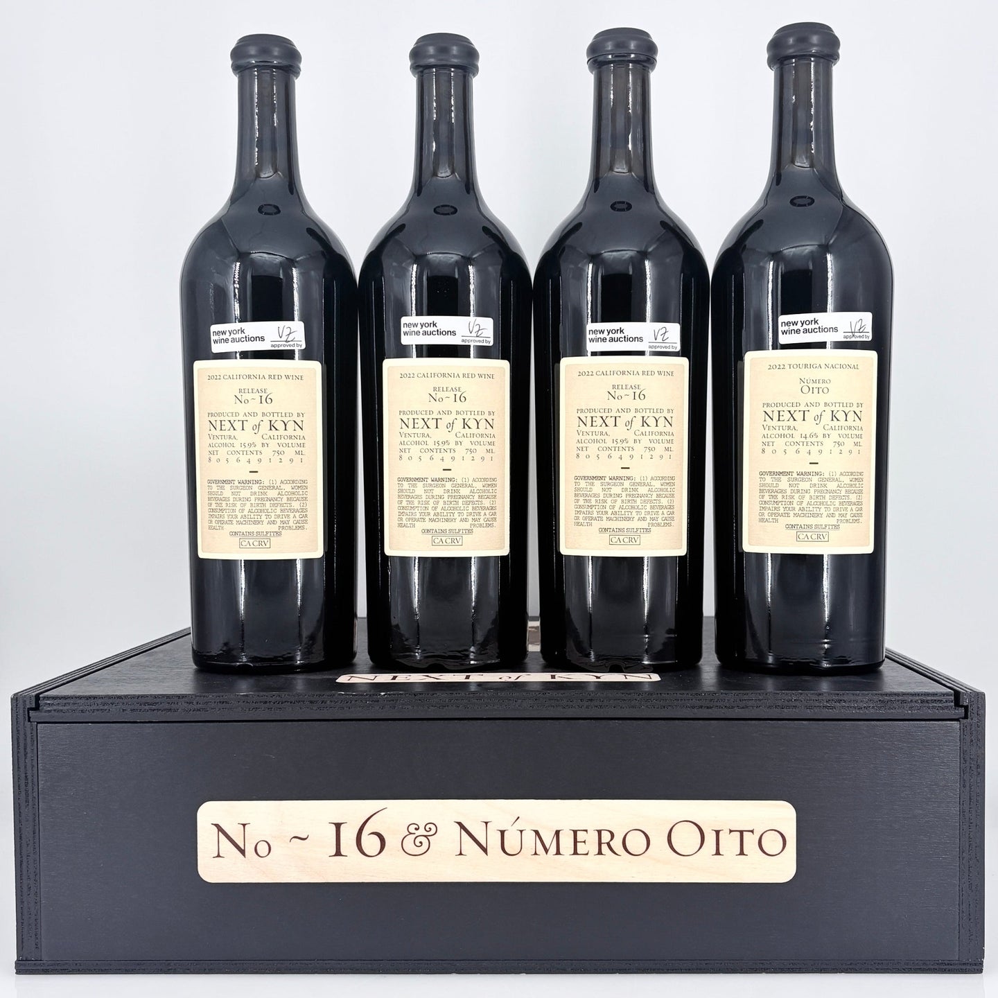 Four bottles of wine from 'Next of Kin' on a black stand with 'No. 16 & Néméro Oito' branding.