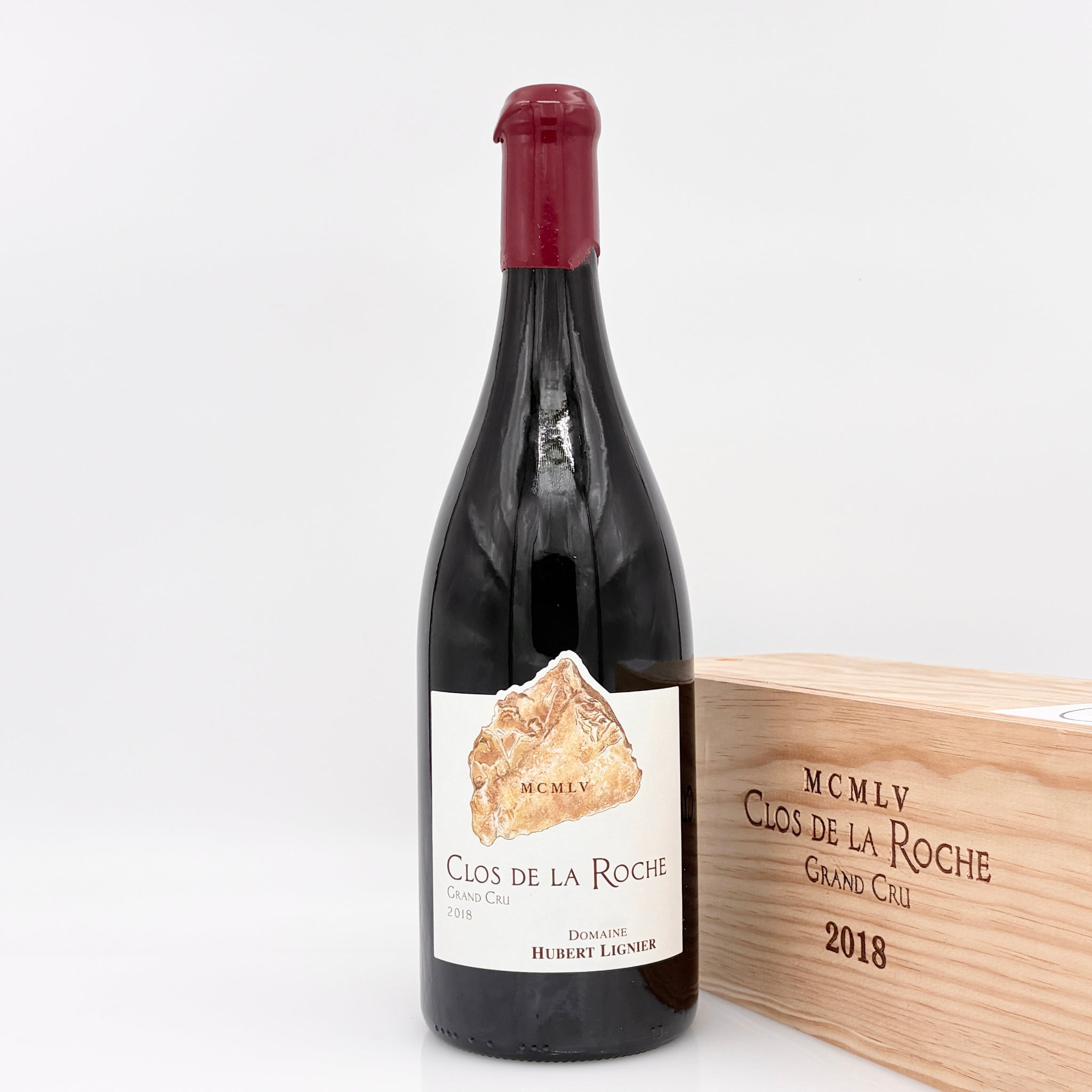 Wine bottle with wooden box labeled 'Clos de la Roche' on a white background