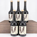 Five bottles of wine with unique labels on a wooden surface.