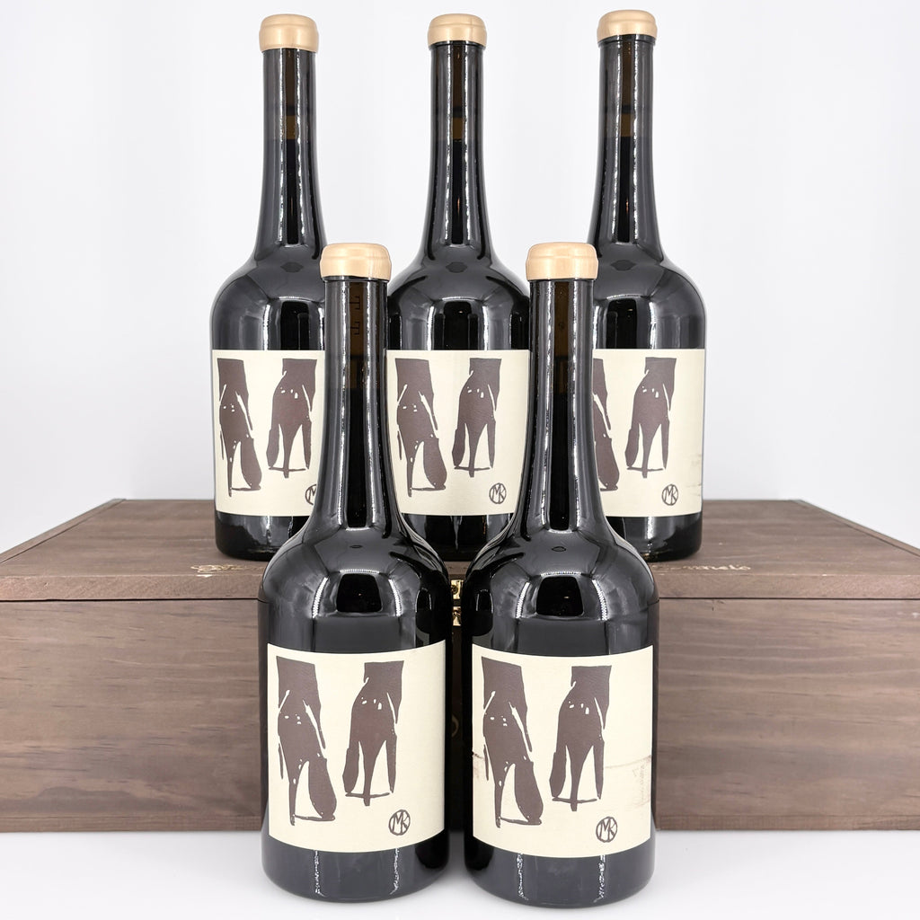 Five bottles of wine with unique labels on a wooden surface.
