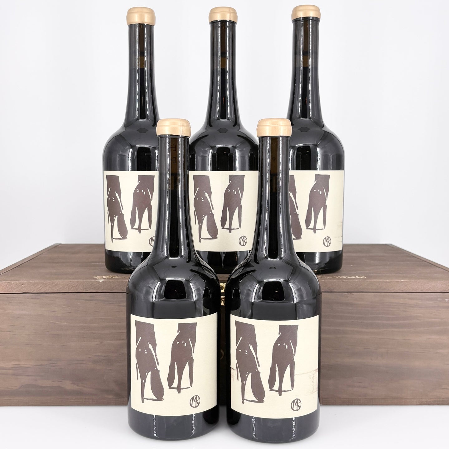 Five bottles of wine with unique labels on a wooden surface.