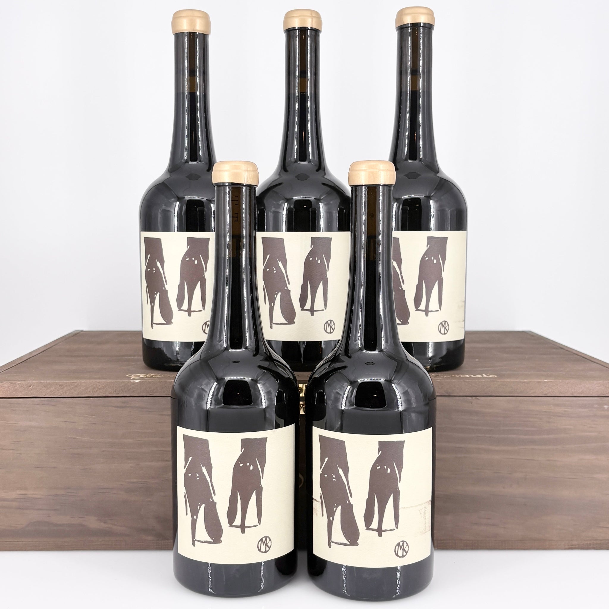 Five bottles of wine with unique labels on a wooden surface.