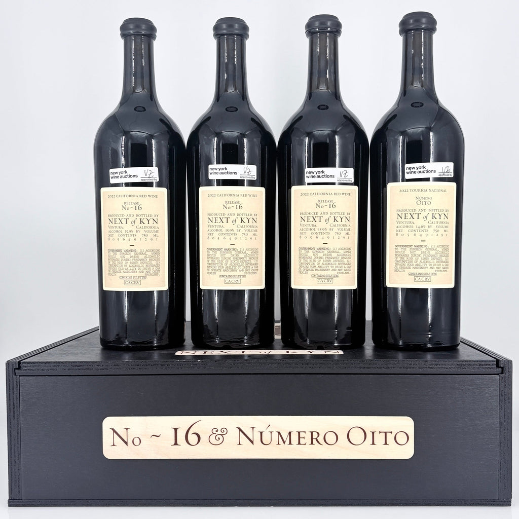 Four bottles of wine from 'Next of Kin' on a black stand with 'No. 16 & Néméro Oito' branding.